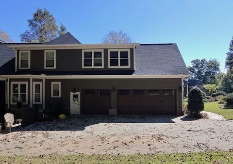 Completed home exterior featuring James Hardie Timber Bark siding, Arctic White trim, second-story dormer windows, and a two-car garage after C&W's siding renovation.