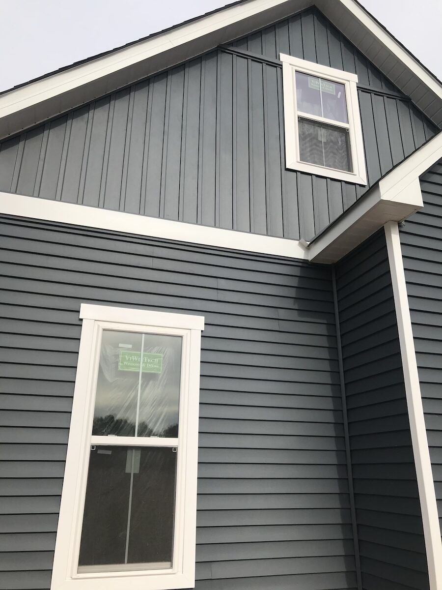 Dark vinyl siding with board and batten gable accents and white replacement windows on a Pickens, SC home